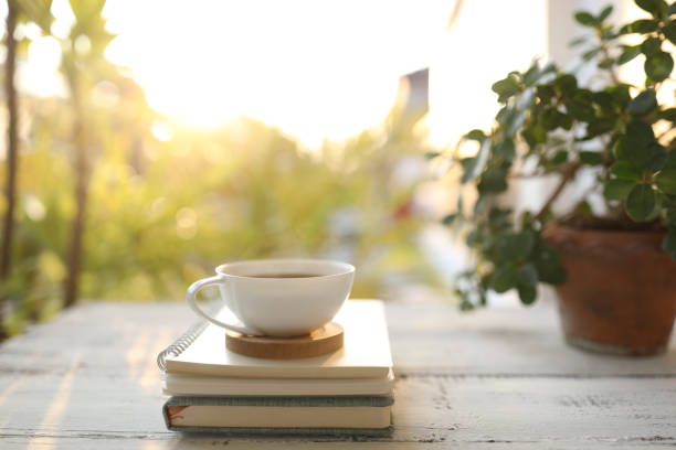 istock Coffee cup and notebook and plant pot on wooden table under sunlight 1397197272