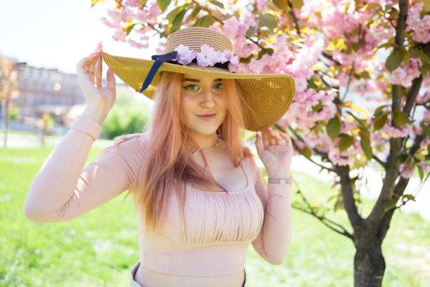 Young girl posing near blossom cherry tree with pink flowers
