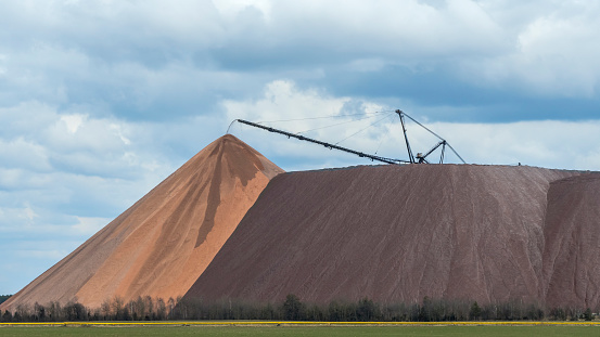 Giant spreader or absetzer machinery. A large dumper on a landfill with potash ore. Extracting and mining potassium salts. Large excavator machine and waste ore in the extraction of potassium.