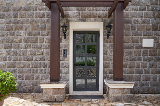 Entrance to the house with glass door and stone finished wall.