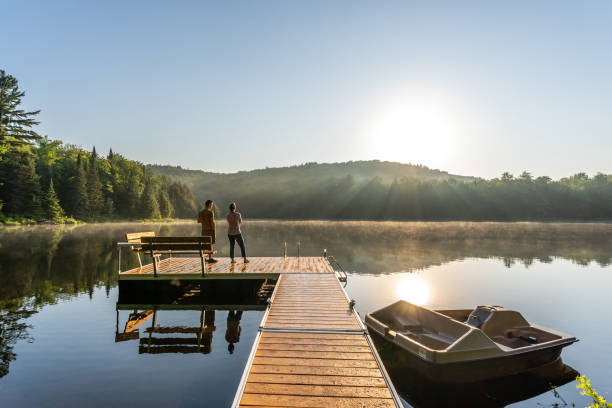 A couple relaxing by a small and quiet fishing lake in the Laurentides (Laurentians), Quebec, during a sunrise of summer.