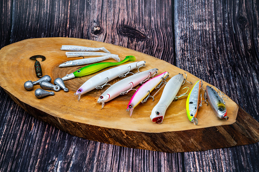 Fishing tackle - fishing spinning, hooks and lures on darken wooden background.