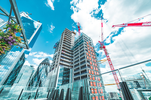 View at construction site with unfinished residential buildings against blue sky, London