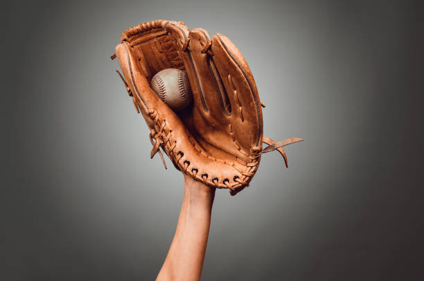 istock Baseball leather glove with white ball on hand on dark gray background. 1397208060