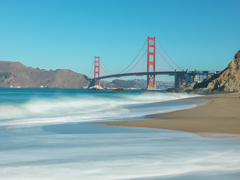 Classic panoramic view of famous Golden Gate Bridge seen from scenic Baker Beach in beautiful morning light on a sunny day with blue sky and clouds in summer, San Francisco, California, USA