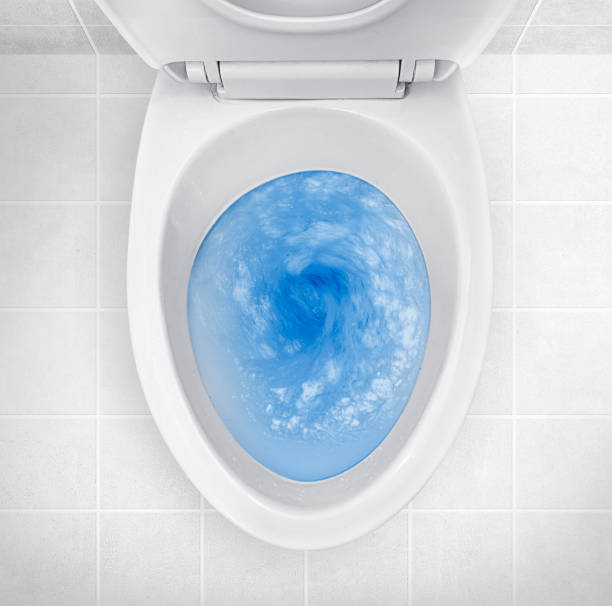 Top view of toilet bowl, blue detergent flushing in it Top view of toilet bowl, blue detergent flushing in it flushing stock pictures, royalty-free photos & images