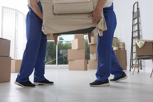 Moving service employees carrying armchair in room, closeup
