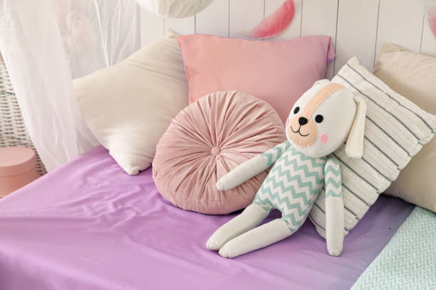 istock Comfortable bed with cushions and toy in room. Interior design 1397221913