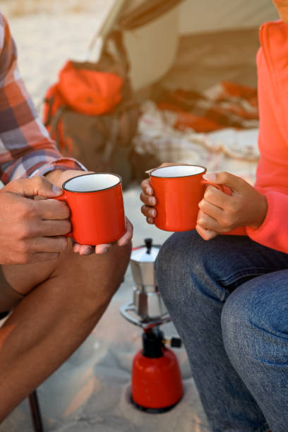 istock Couple with cups of hot drinks outdoors, closeup. Beach camping 1397223168