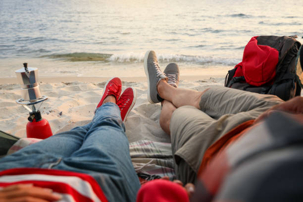 casal descansando perto do mar, close-up. acampamento na praia - sunrise beach couple hiking - fotografias e filmes do acervo