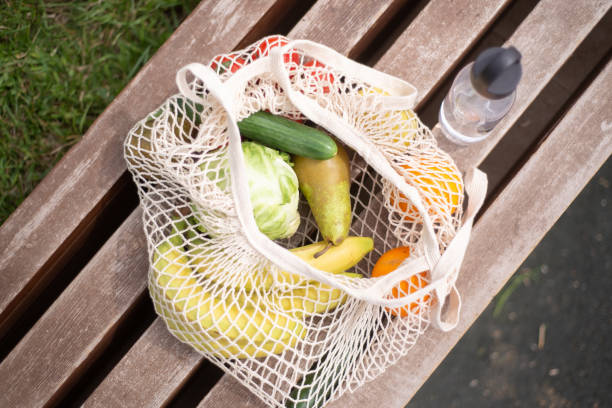 paquet écologique de produits sur le banc - onion bag netting vegetable photos et images de collection