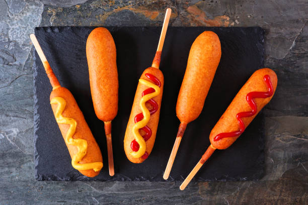 кукурузные собачки на блюдечке с шифером - corn dog стоковые фото и изображения