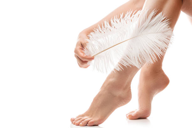 weibliche füße mit glatter haut und weicher straußenfeder auf weißem hintergrund - smooth human skin human leg human foot stock-fotos und bilder