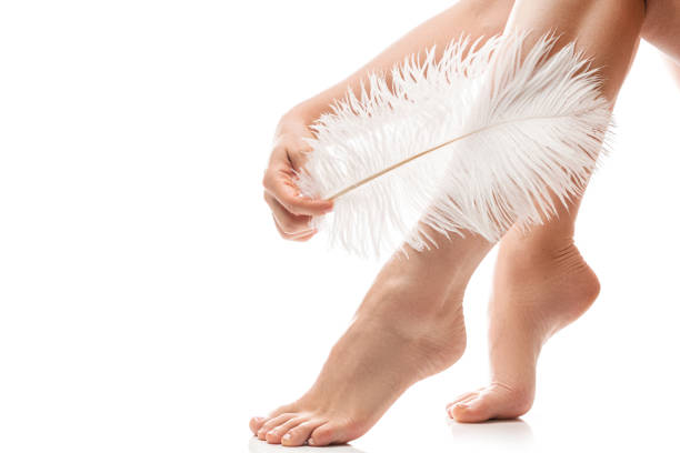 istock Female feet with smooth skin and soft ostrich feather on white background 1397227907