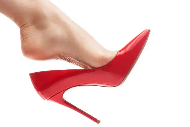 Photo of Female foot with red stiletto heels shoe on white background