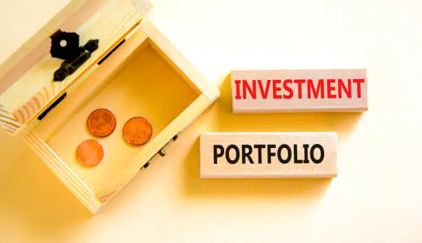 Photo of Investment portfolio symbol. Wooden blocks with concept words Investment portfolio on white background. Wooden chest with coins. Business investment portfolio concept. Copy space.