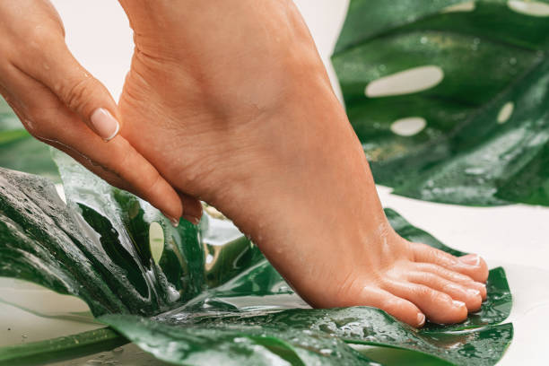 Wet female feet with smooth skin and tropical leaves stock photo