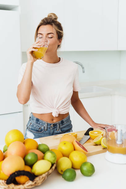 istock Woman drinking freshly squeezed homemade orange juice in white kitchen 1397231075