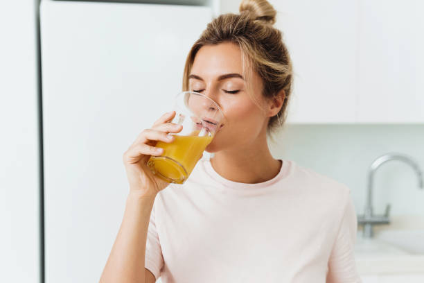 istock Woman drinking freshly squeezed homemade orange juice in white kitchen 1397231081