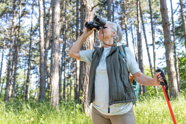 istock Senior woman leaning onto a hiking pole and using binoculars on a hike 1397232445