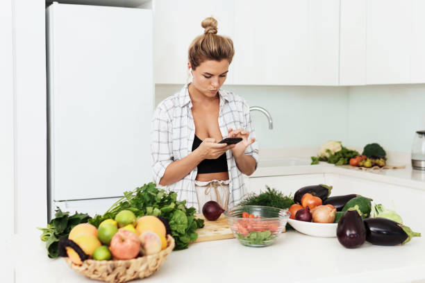istock Woman with wireless earbuds is using smartphone during cooking in modern white kitchen 1397232623