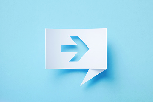 Rectangular shaped white chat bubble with cutout arrow symbol sitting on blue background. Horizontal composition with copy space.