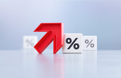 Red up arrow and percentage sign written white cubes sitting on before defocused background. Horizontal composition with copy space.