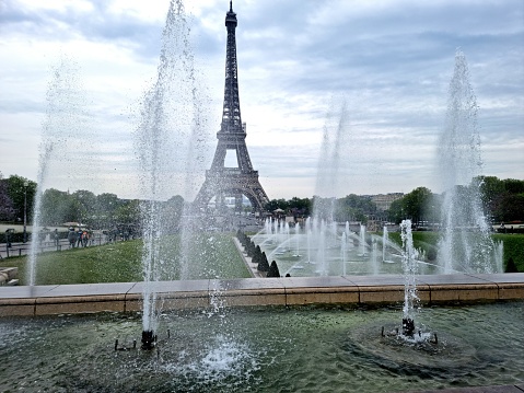 The famous Eiffel Tower seen in springseason with twith several faintins in front of. This landmark was constructed from 1887 to 1889 as the entrance to the 1889 World's Fair.
