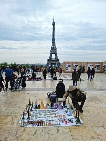 The famous Eiffel Tower seen in springseason with twith several souvenir sellers in front of. This landmark was constructed from 1887 to 1889 as the entrance to the 1889 World's Fair.