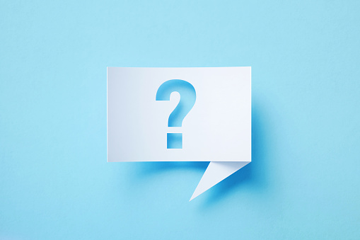 Rectangular shaped white chat bubble with cutout question mark sitting on blue background. Horizontal composition with copy space.