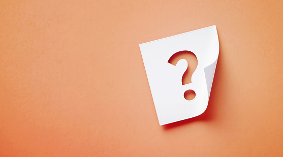 White adhesive note with cutout question mark sitting on orange background. Horizontal composition with copy space.