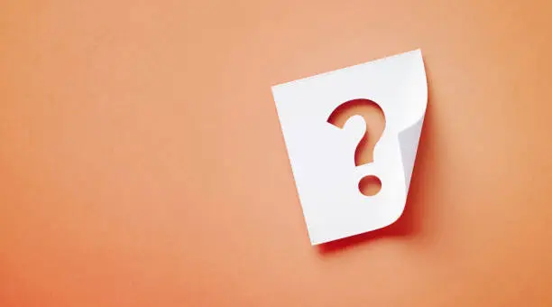 Photo of White Adhesive Note With Cutout Question Mark Sitting Over Orange Background