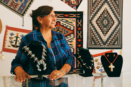A female Indigenous Navajo small business owner at work in her jewelry shop.