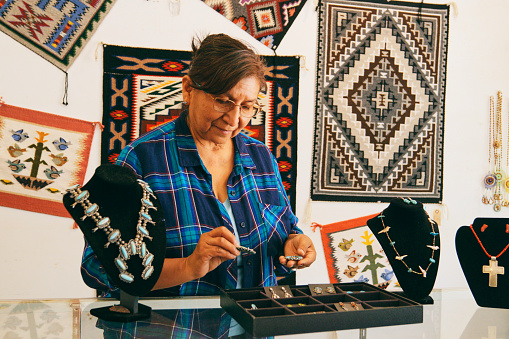 A female Indigenous Navajo small business owner at work in her jewelry shop.