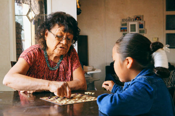 할머니와 손자가 게임을하고 있습니다. - native american north american tribal culture women mature adult 뉴스 사진 이미지