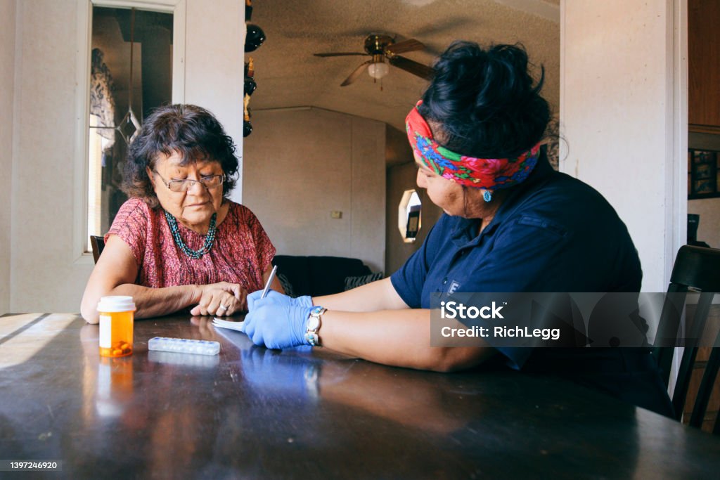 Senior Healthcare Assistance in a Home An Indigenous Navajo senior aged woman, receiving healthcare assistance in her home. Indigenous Peoples of the Americas Stock Photo
