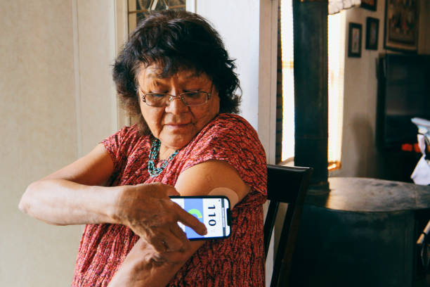 mujer mayor que revisa el nivel de glucosa en sangre en una aplicación - diabetes fotografías e imágenes de stock