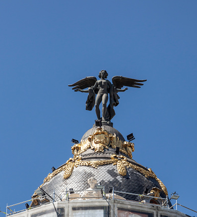 Madrid, Spain - 25th April 2022. Victoria Alada. a bronze Winged Victory (Nike) by Federico Coullaut-Valera, placed on top of the Edificio Metrópolis in central Madrid, Spain.