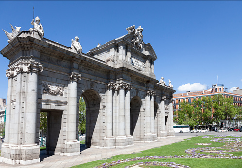 Madrid, Spain - 25th April 2022. Puerta de Alcalá / Acala Gate, the oldest of the triumphal gates into the city of Madrid, Spain. ( Francesco Sabatini, 1759, Plaza de la Independencia) The centre sculpture is of the Royal Coat of Arms held by Fame and a child. The four sculptures of children symbolise  fortitude, justice, temperance and prudence.