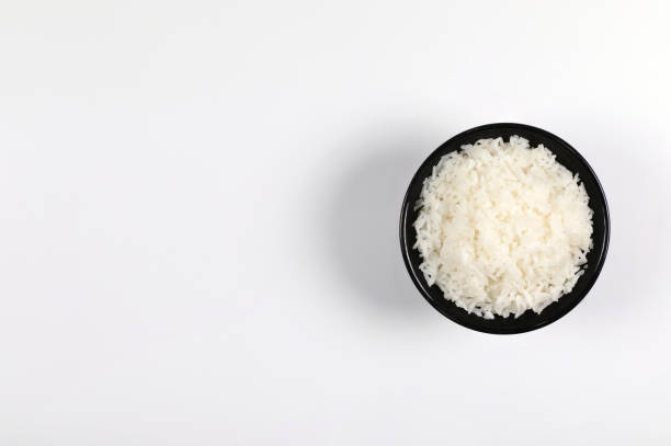il riso in ciotola nera su sfondo bianco vista dall'alto hanno spazio di copia. - clipping path rice white rice basmati rice foto e immagini stock