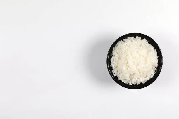 Photo of Rice in black bowl on white background top view have copy space.