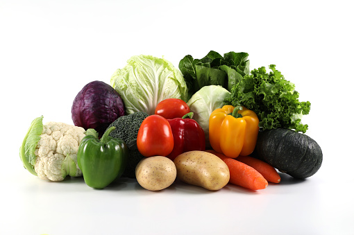 Large and colorful variation of vegetables and fruits on white background (broccoli, melon, bell peppers, lettuce, grapes, apples, limes, watermelon, strawberries, cauliflower, eggplants, onions, potatoes, corn, avocado, tomatoes, mangoes, oranges, bananas, passion fruit, green cabbage, purple cabbage, carrots, green beans, pineapple, guava, chili peppers). Studio isolated.