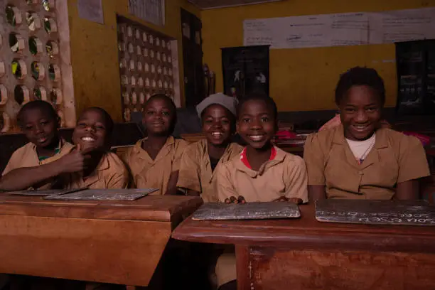 Group of pupils sitting at school desks with their blackboards happy laughing.