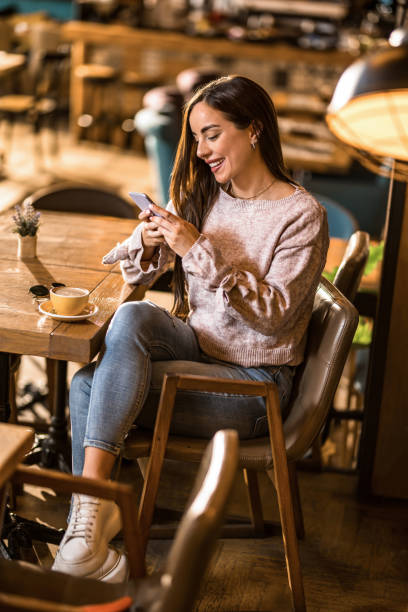 istock Happy young woman using phone in a coffee shop. 1397260241
