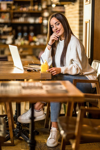 istock Happy young woman using laptop and looking at camera in a cafe. 1397261125