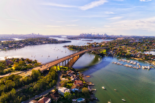 Entire Gladesville bridge across Parramatta river in Sydney West - aerial cityscape towards city CBD skyline.