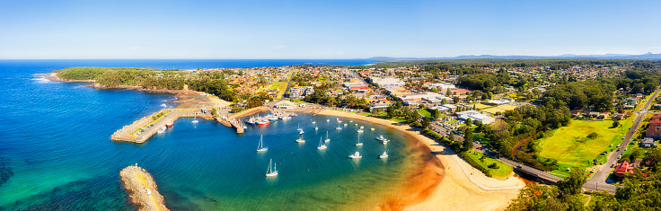 Protected sea harbour in Ulladulla town on Sapphire coast of Australia - aerial panorama over downtown and shores line.