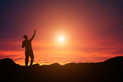 3d silhouette of a man with arms raised against a sunset ocean landscape