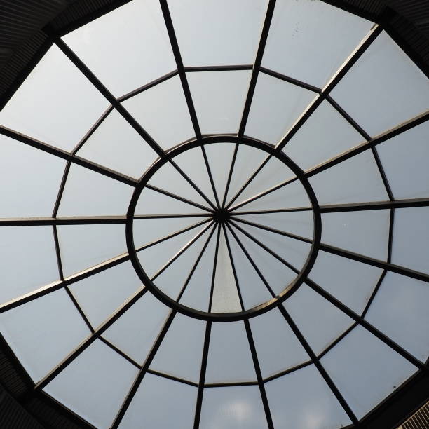 cúpula de vidrio o ventana redonda en el techo. el cielo se puede ver a través de una estructura transparente de vidrio en la bóveda del edificio. motivos arquitectónicos de moda en la construcción moderna. una gran ventana redonda - dome skylight stained glass glass fotografías e imágenes de stock