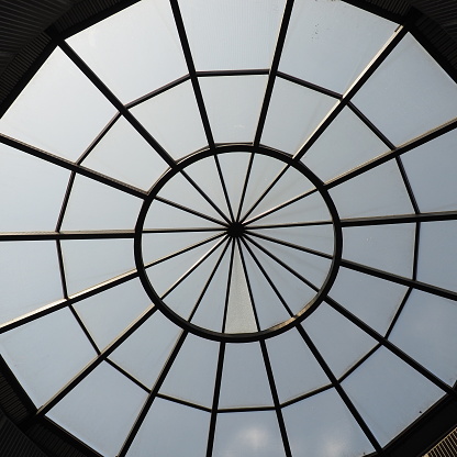 Glass dome or round window in the roof. The sky can be seen through a glass transparent structure in the vault of the building. Architectural fashion motifs in modern construction. A big round window